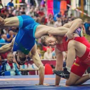 Wrestler with his legs out while standing on one hand.