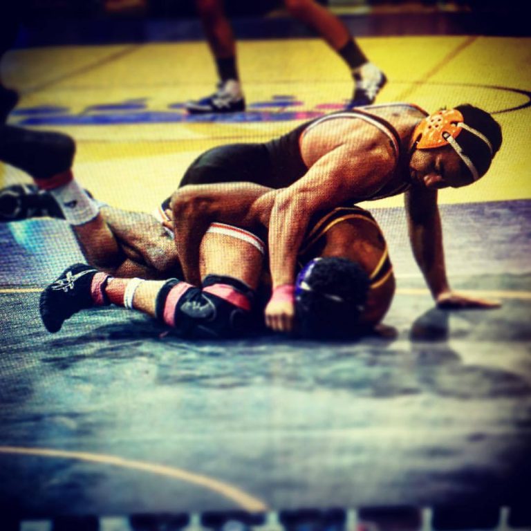 Two wrestlers wrestling on the mat